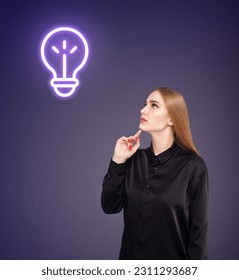 Young woman in black shirt with glowing bulb over head. Over dark blue background. - Shutterstock ID 2311293687
