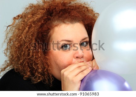 young woman in black shirt inflating balloon