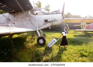 Young Woman In A Black Skirt Towing Her Luggage On A Vintage Airfield