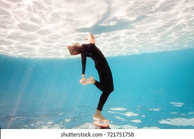 Young Woman In Black Sport Suit Swim And Dive Underwater Floating Pool With Transparent Water In Beautiful Mysterious Underwater World. Fantastic Fairy Dreamy Mood. Water Safety Or Yoga Class