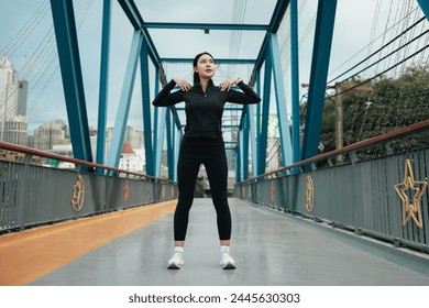 young woman in black sportswear exercise lightly on the bridge in the morning. - Powered by Shutterstock