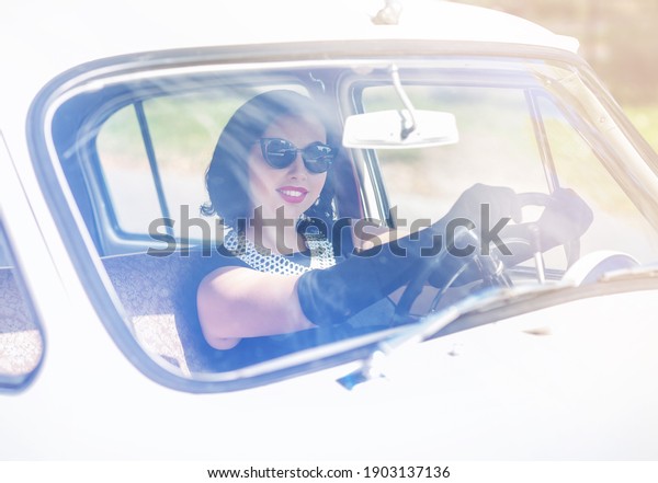 young woman in black sunglasses driving a retro car,\
sunny summer day