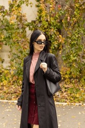 Young Woman In Black Sunglasses And Leather Raincoat. Natural. Attractive Woman In Park. Youth Fashion