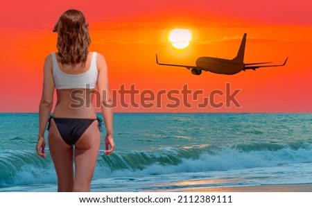 Young woman in black and white  bikini on the beach with airplane on background