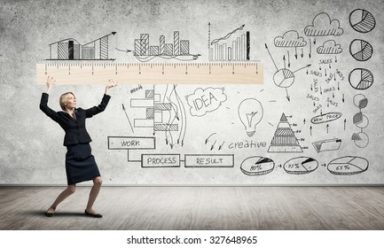 Young woman at blackboard measuring something with big ruler - Powered by Shutterstock