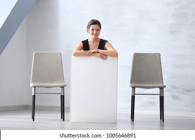 Young woman with blank advertising board indoors - Shutterstock ID 1005646891