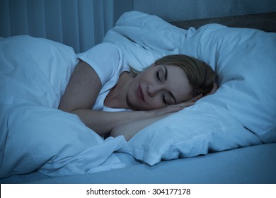 Young Woman With Blanket Sleeping At Night In Bed