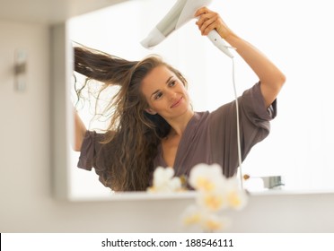 Young Woman Blow Drying Hair In Bathroom