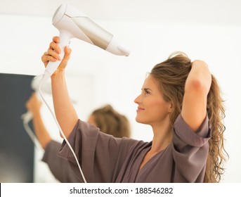 Young Woman Blow Drying Hair In Bathroom