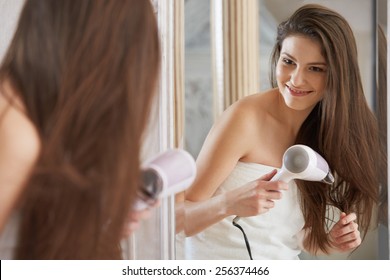 Young Woman Blow Drying Hair In Bathroom