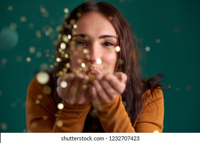 young woman blowing confetti from hands, gold glittery sparkly glamourous colour combination - Powered by Shutterstock