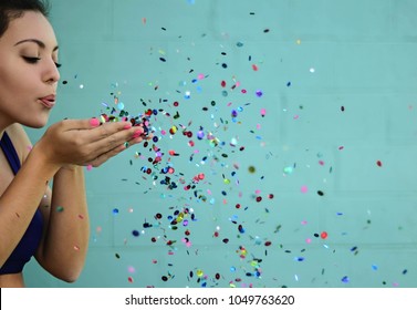 Young Woman Blowing Glitter In Sports Bra On Blue Background