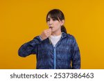 Young woman blowing whistle on orange background