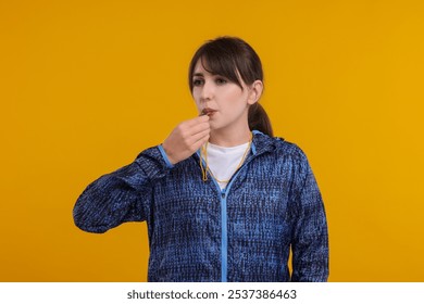 Young woman blowing whistle on orange background - Powered by Shutterstock