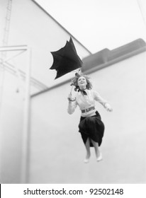 Young Woman Is Blown Away, Jumping From A Roof With An Umbrella