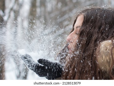 A Young Woman Blows Snow Off Her Gloves. Falling Snow