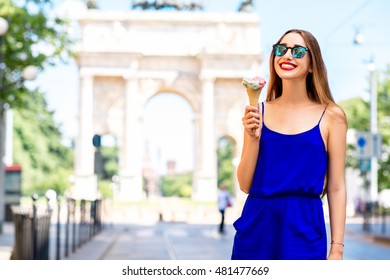 Young Woman In The Blue Dress Eating Ice Cream In Front Of The Triumphal Arch In Milan. Street Food In Milan