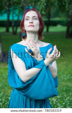 Young woman in blue fantasy dress standing in the forest