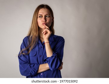 Young woman in blue full of doubts and hesitation. Woman solving a problem.