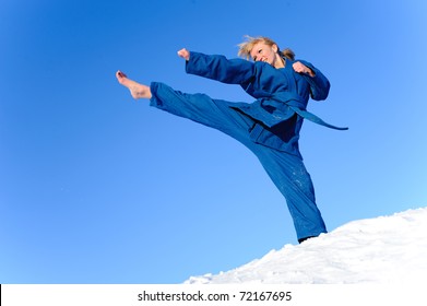 young woman in blue kimono stand on snow and exercising kicking