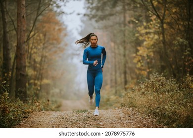 Young Woman In Blue Track Suit Running Toward Camera On The Forest Trail At Autumn