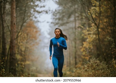 Young Woman In Blue Track Suit Running Toward Camera On The Forest Trail At Autumn