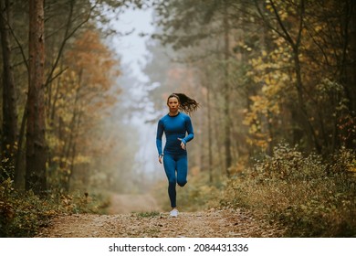 Young Woman In Blue Track Suit Running Toward Camera On The Forest Trail At Autumn