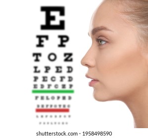 Young Woman And Blurred Eye Chart On Background. Visiting Ophthalmologist 