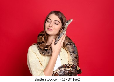 Young Woman With Boa Constrictor On Red Background. Exotic Pet