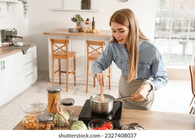 Young woman boiling pasta in kitchen - Powered by Shutterstock