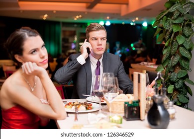 Young Woman Bored To Date While Her Boyfriend Having Business Cell On Mobile Phone