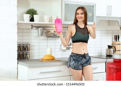 Young Woman With Bottle Of Protein Shake In Kitchen