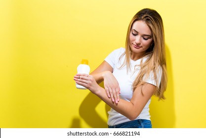 Young Woman A Bottle Of Sunblock On A Yellow Background