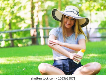 Young Woman A Bottle Of Sunblock Outside On A Summer Day