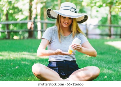 Young Woman A Bottle Of Sunblock Outside On A Summer Day