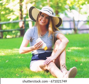 Young Woman A Bottle Of Sunblock Outside On A Summer Day