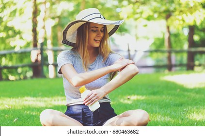 Young Woman A Bottle Of Sunblock Outside On A Summer Day