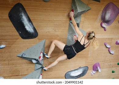 Young Woman Bouldering In A Climb Gym