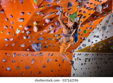Young Woman Bouldering In Climbing Gym