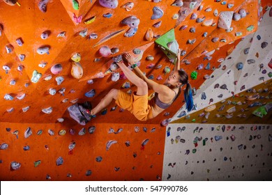 Young Woman Bouldering In Climbing Gym