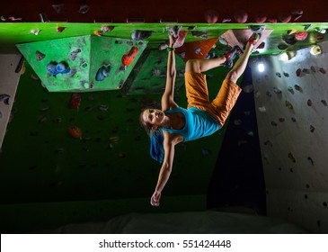 Young Woman Bouldering In Climbing Gym 