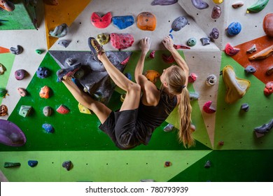 Young Woman Bouldering In Indoor Climbing Gym