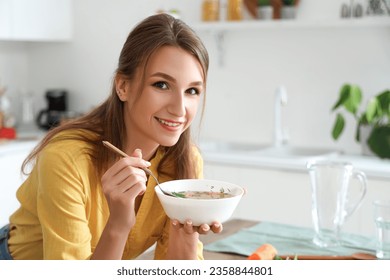 Young woman with bowl of chicken soup in kitchen, closeup - Powered by Shutterstock