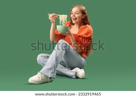 Young woman with bowl of Chinese noodles sitting on green background