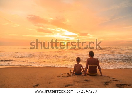 Young woman and boy, mother and son sitting on the beach at sunset, Kalutara, Sri Lanka