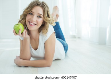 Young Woman In Braces With Apple