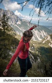 Young woman with braided hair is balancing on a view point in Julian Alps during her hike on a sunny September day.