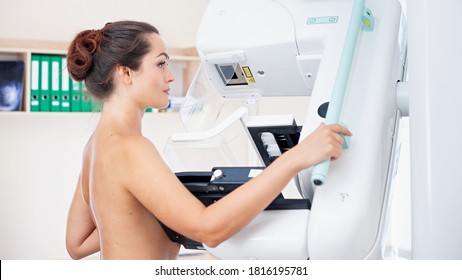 Young woman at breast cancer prevention screening at hospital. Hardware examination of the breast. Healthy young woman doing cancer prophylactic mammography scan. Modern hospital with hi-tech machine - Shutterstock ID 1816195781