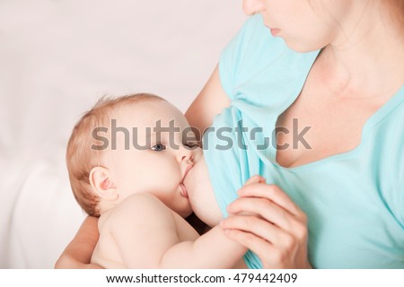 A young woman breast-feeding a baby sitting in a chair