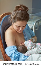 Young Woman Breastfeeding Newborn Baby On Hospital Room Background